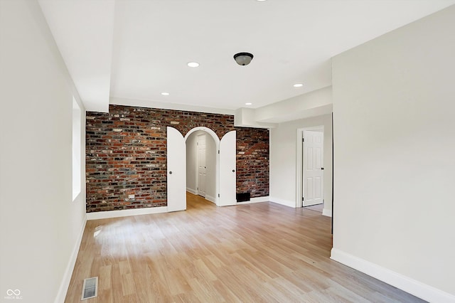 8602 Frontgate Ln, Indianapolis, IN 46256 - empty room with brick wall, baseboards, light wood-style flooring, arched walkways, and recessed lighting