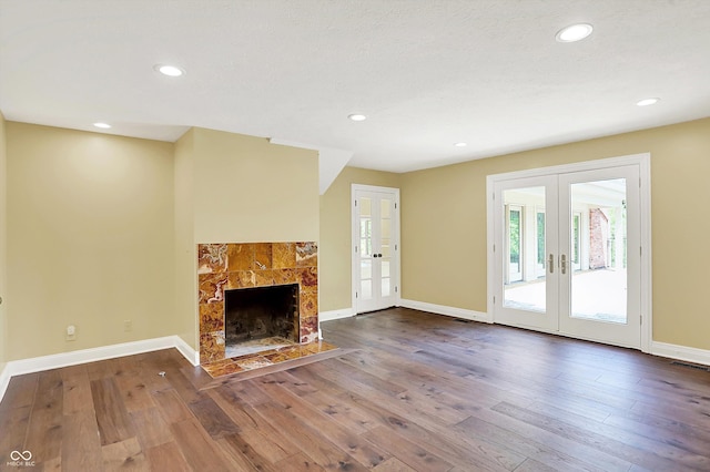 8602 Frontgate Ln, Indianapolis, IN 46256 - unfurnished living room featuring french doors, wood-type flooring, a tiled fireplace, recessed lighting, and baseboards