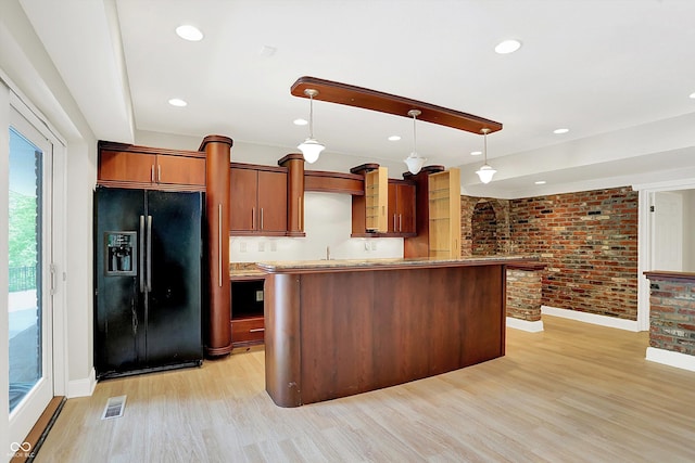 8602 Frontgate Ln, Indianapolis, IN 46256 - kitchen featuring black fridge with ice dispenser, brick wall, baseboards, light wood-style flooring, and decorative light fixtures