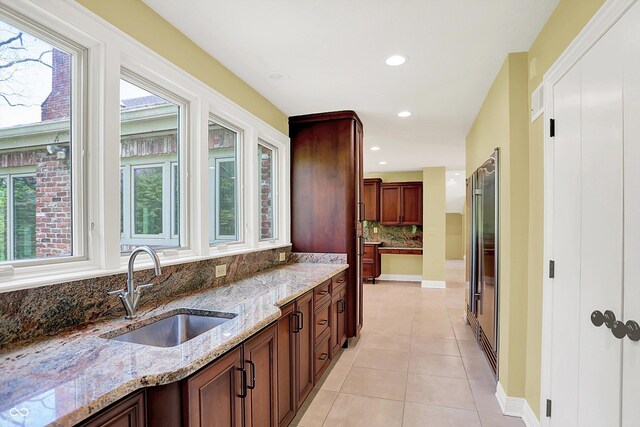 8602 Frontgate Ln, Indianapolis, IN 46256 - kitchen featuring a sink, tasteful backsplash, light tile patterned floors, light stone countertops, and recessed lighting