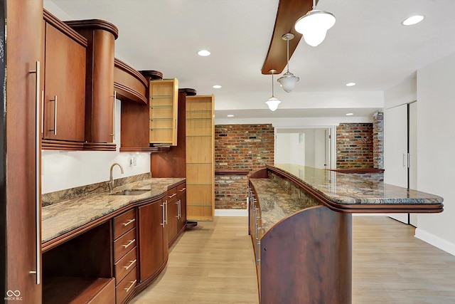 8602 Frontgate Ln, Indianapolis, IN 46256 - kitchen featuring a sink, brick wall, light wood-style flooring, baseboards, and a center island