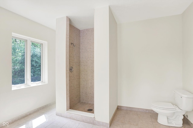 8602 Frontgate Ln, Indianapolis, IN 46256 - bathroom featuring tiled shower, toilet, tile patterned flooring, and baseboards