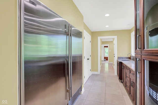 8602 Frontgate Ln, Indianapolis, IN 46256 - kitchen with high end refrigerator, a sink, light stone countertops, light tile patterned floors, and recessed lighting