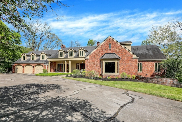 8602 Frontgate Ln, Indianapolis, IN 46256 - cape cod-style house featuring brick siding, a porch, a chimney, driveway, and a front lawn