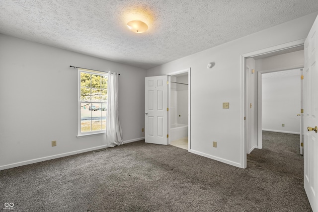 unfurnished bedroom featuring ensuite bathroom, a textured ceiling, and dark carpet