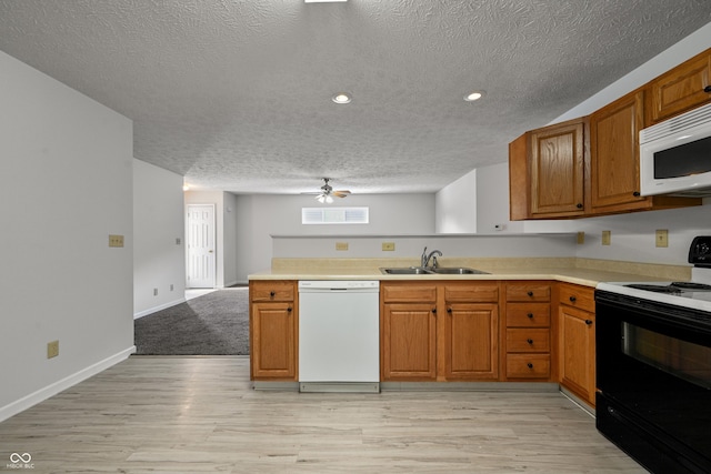 kitchen with sink, white appliances, light hardwood / wood-style floors, kitchen peninsula, and a textured ceiling