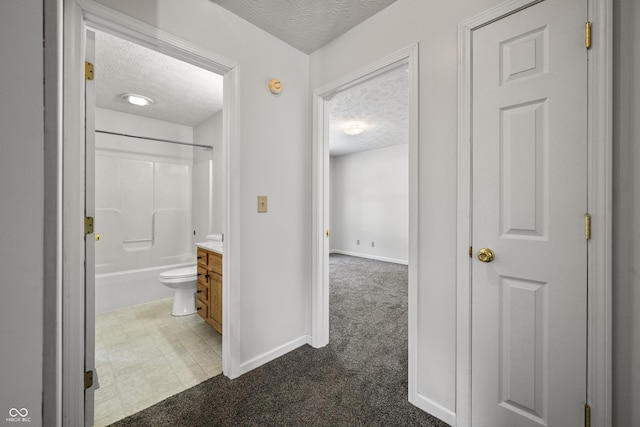 hallway featuring dark carpet and a textured ceiling