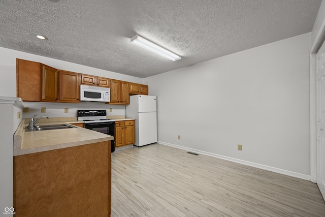 kitchen featuring sink, white appliances, light hardwood / wood-style floors, and a textured ceiling