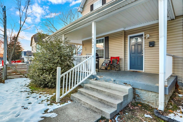 snow covered property entrance with covered porch