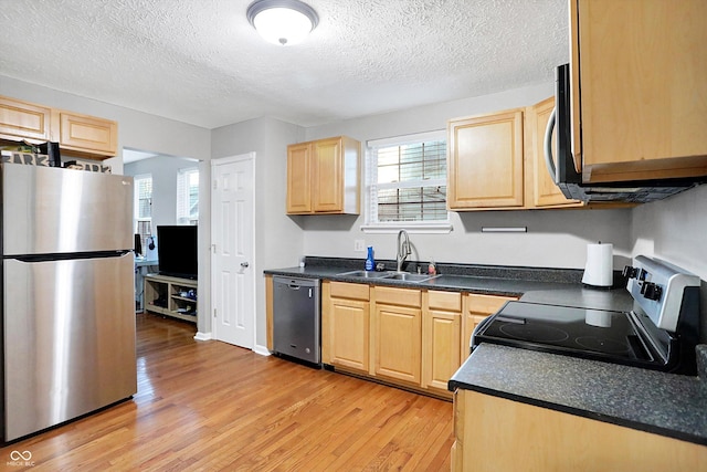 kitchen featuring light brown cabinetry, sink, a textured ceiling, stainless steel appliances, and light hardwood / wood-style floors