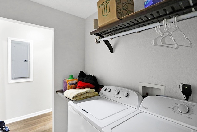 laundry area featuring light hardwood / wood-style flooring, washing machine and clothes dryer, and electric panel