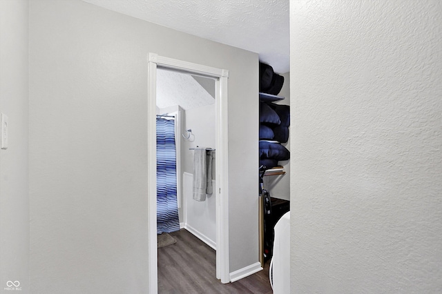 hall with dark wood-type flooring and a textured ceiling