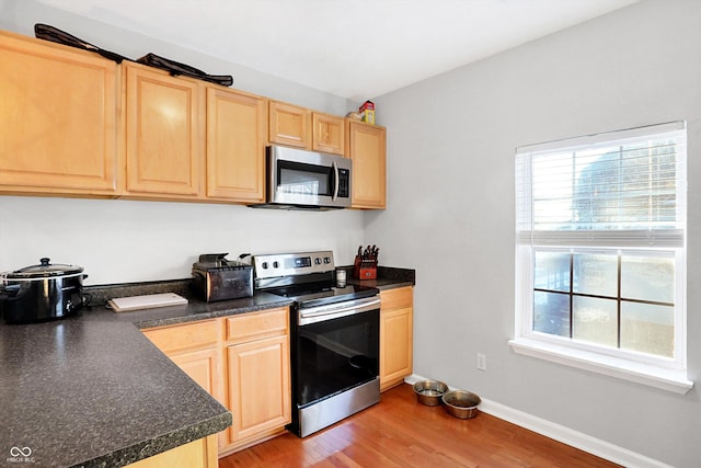 kitchen featuring appliances with stainless steel finishes, light brown cabinetry, and light hardwood / wood-style flooring