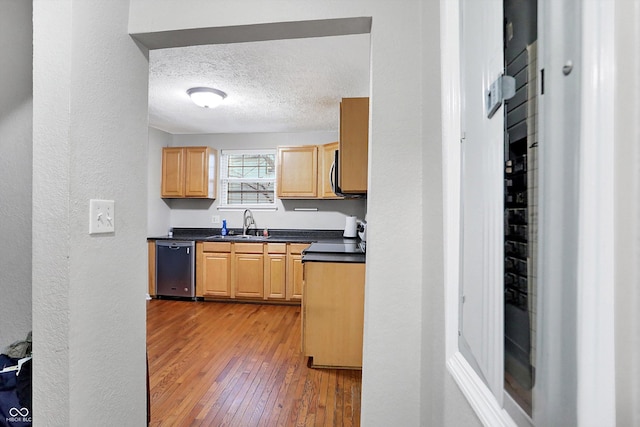 kitchen featuring sink, light hardwood / wood-style flooring, black dishwasher, a textured ceiling, and light brown cabinets