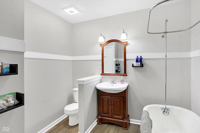 bathroom with hardwood / wood-style floors, vanity, a bath, and toilet