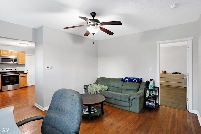 living room with ceiling fan and dark hardwood / wood-style flooring