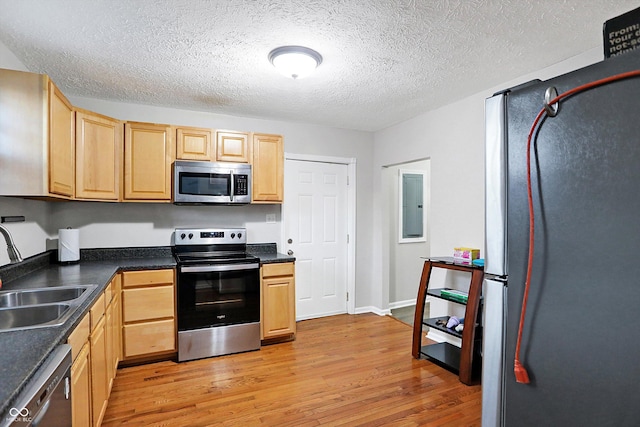 kitchen featuring light brown cabinetry, sink, electric panel, stainless steel appliances, and light wood-type flooring