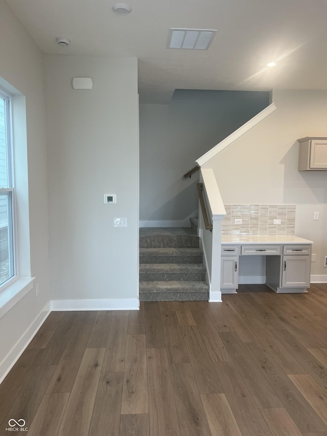 staircase featuring visible vents, baseboards, and wood finished floors