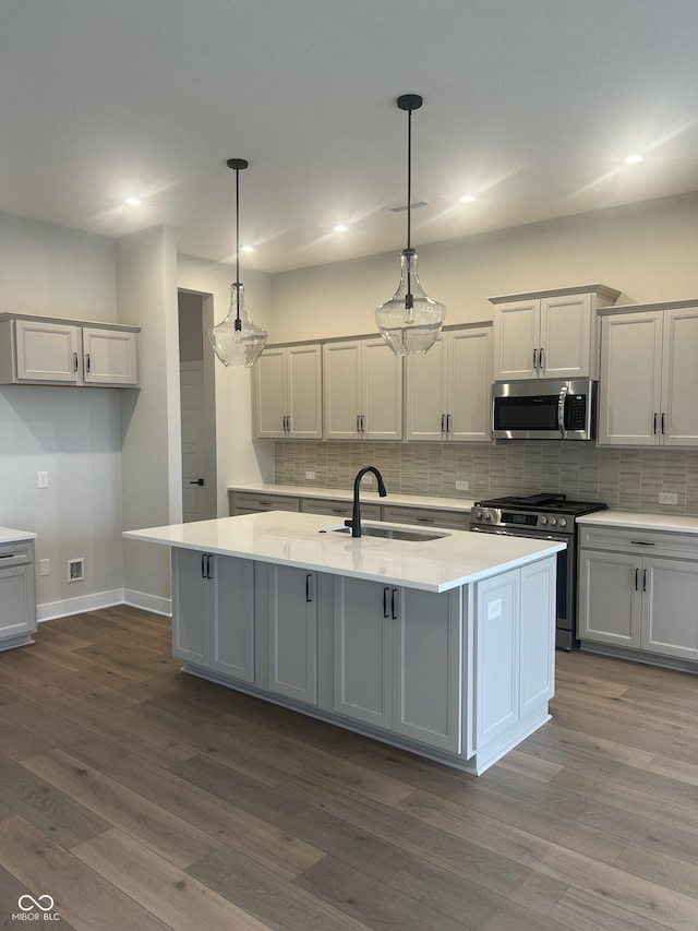 kitchen featuring light countertops, appliances with stainless steel finishes, decorative backsplash, and a sink