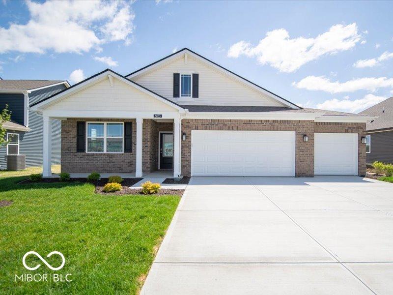 view of front of home with cooling unit, concrete driveway, an attached garage, brick siding, and a front lawn