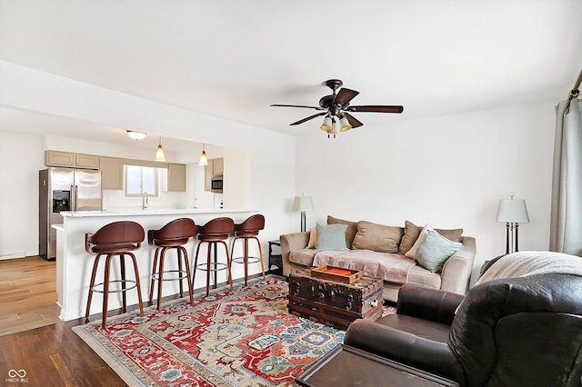 living room featuring hardwood / wood-style flooring, ceiling fan, and sink