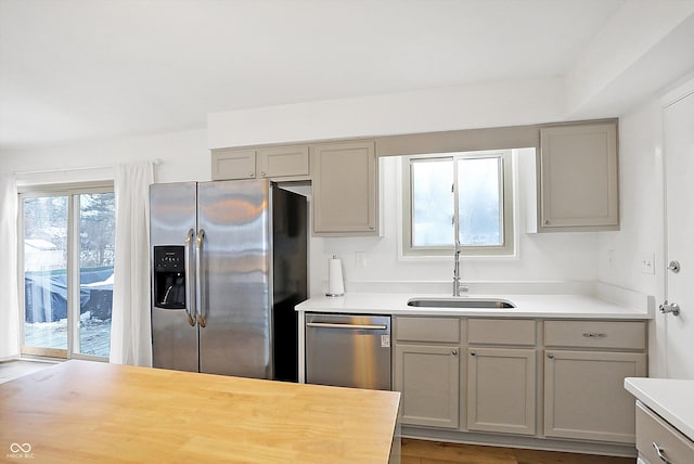 kitchen featuring butcher block counters, appliances with stainless steel finishes, sink, and gray cabinetry