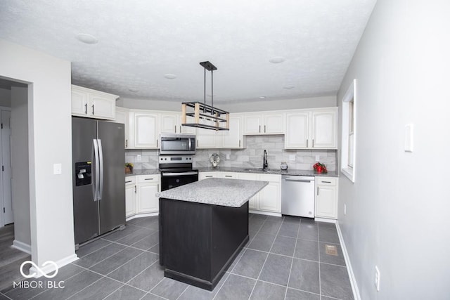 kitchen featuring pendant lighting, white cabinetry, a kitchen island, and appliances with stainless steel finishes