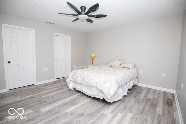 bedroom with ceiling fan, wood-type flooring, and a textured ceiling