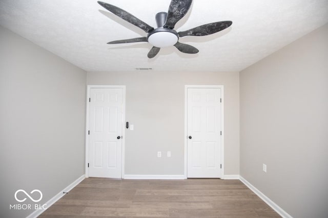 unfurnished bedroom featuring a textured ceiling, wood-type flooring, and ceiling fan