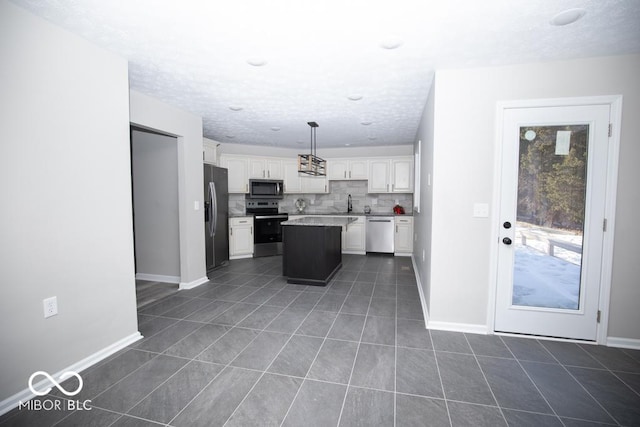 kitchen featuring white cabinetry, a center island, dark tile patterned flooring, pendant lighting, and stainless steel appliances