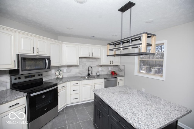 kitchen featuring stainless steel appliances, white cabinetry, hanging light fixtures, and sink