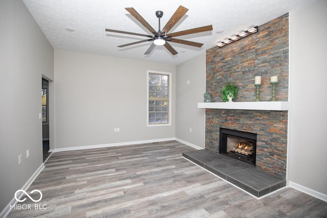 unfurnished living room featuring ceiling fan, hardwood / wood-style flooring, a fireplace, and a textured ceiling