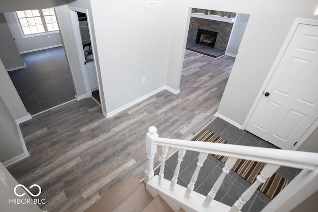 stairway with hardwood / wood-style floors and a stone fireplace