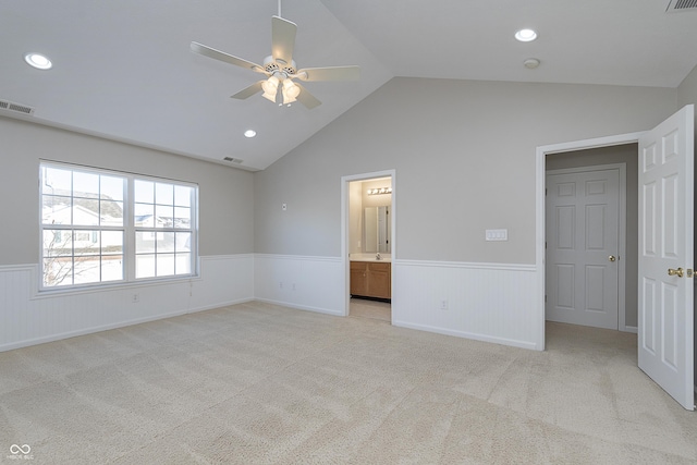 unfurnished bedroom featuring ceiling fan, connected bathroom, vaulted ceiling, and light carpet