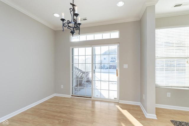 doorway featuring an inviting chandelier, ornamental molding, and light hardwood / wood-style floors