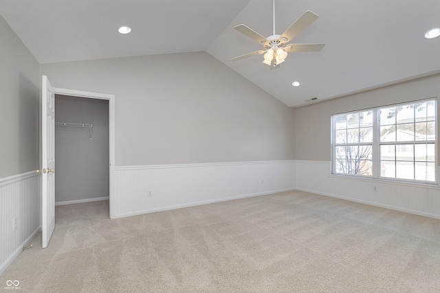 carpeted spare room featuring vaulted ceiling and ceiling fan