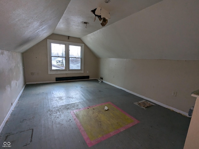 additional living space featuring hardwood / wood-style flooring, lofted ceiling, and a textured ceiling