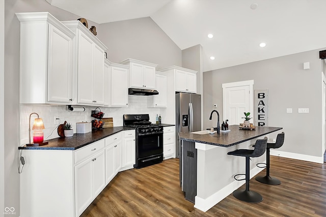 kitchen featuring tasteful backsplash, white cabinetry, a kitchen bar, a kitchen island with sink, and black range with gas cooktop