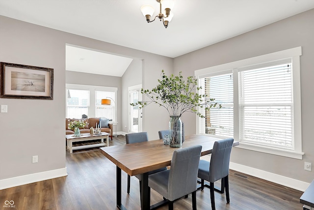 dining space with dark wood-type flooring, lofted ceiling, an inviting chandelier, and a wealth of natural light