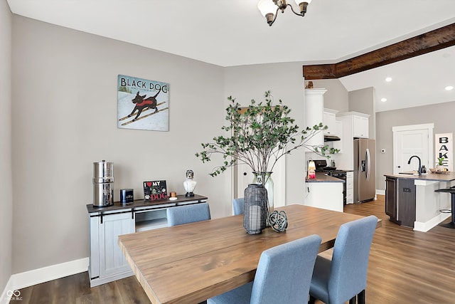 dining area with sink, dark wood-type flooring, and vaulted ceiling with beams