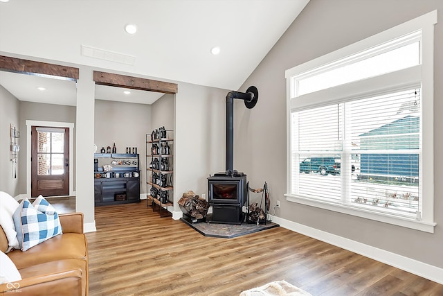 living room with lofted ceiling, plenty of natural light, wood-type flooring, and a wood stove