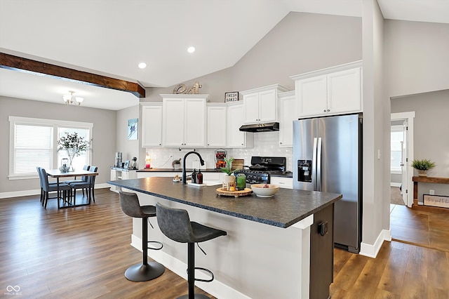 kitchen with stainless steel fridge, a breakfast bar, black gas stove, white cabinetry, and a center island with sink