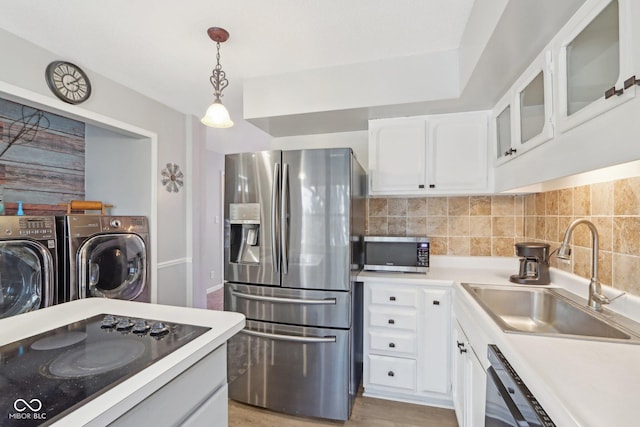 kitchen featuring sink, white cabinetry, decorative light fixtures, separate washer and dryer, and black appliances