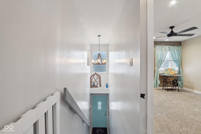 stairway featuring carpet flooring and ceiling fan with notable chandelier