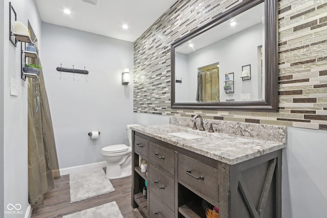 bathroom with hardwood / wood-style flooring, vanity, backsplash, and toilet