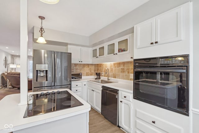 kitchen featuring pendant lighting, sink, black appliances, and white cabinets