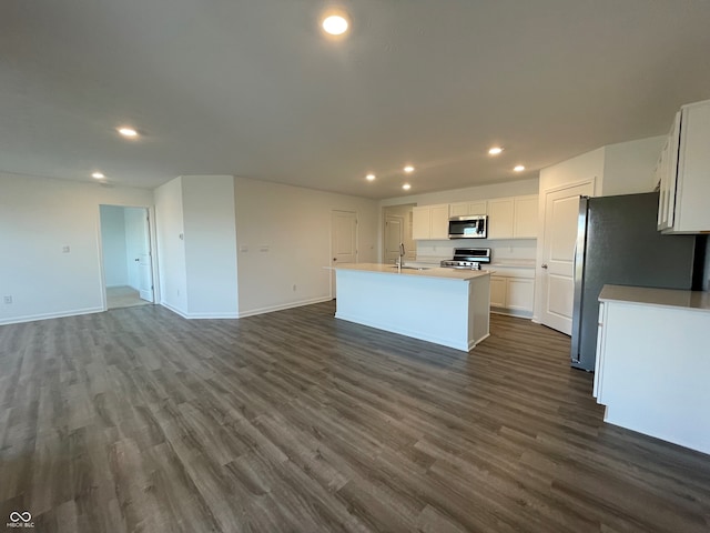 kitchen with sink, appliances with stainless steel finishes, dark hardwood / wood-style floors, white cabinets, and a center island with sink