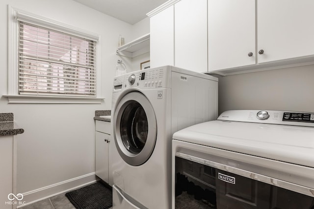 laundry room featuring washing machine and dryer, cabinets, and dark tile patterned floors