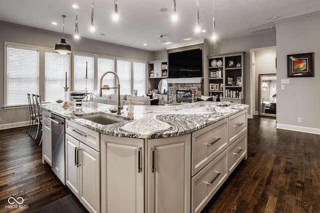 kitchen with sink, hanging light fixtures, light stone countertops, an island with sink, and stainless steel dishwasher