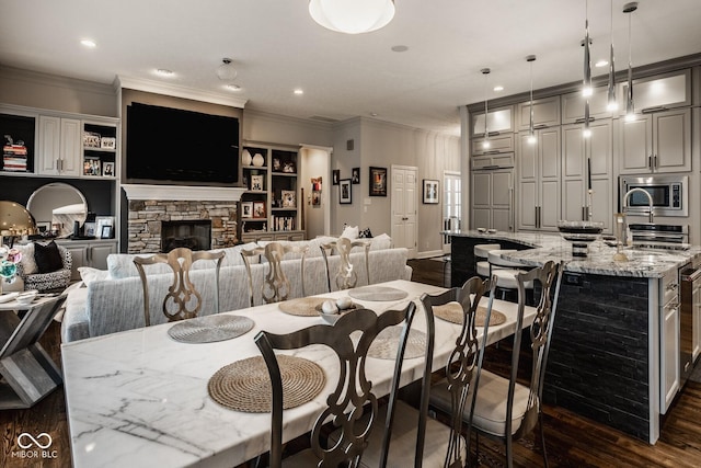 dining space featuring crown molding, a fireplace, and dark hardwood / wood-style flooring